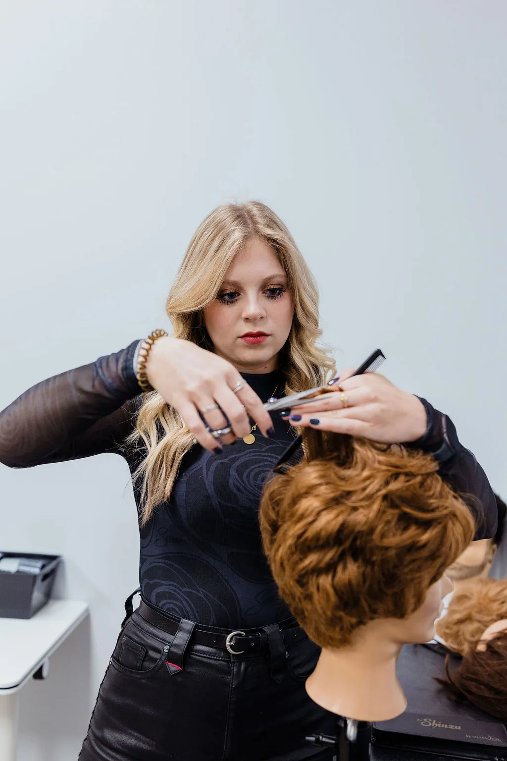 An Elevate student practicing a precision haircut on a mannequin in the training studio