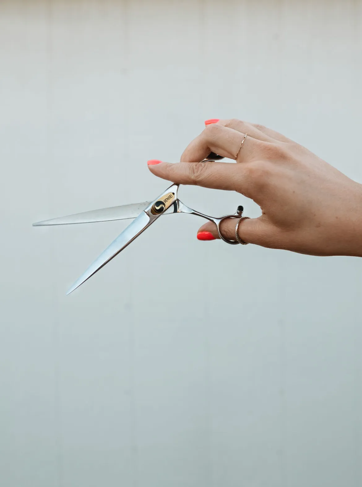 A stylist's hand holding open professional shears