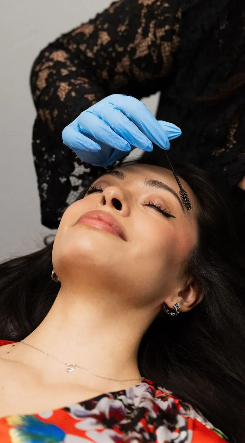 An Elevate student shaping a guest’s brows during a skin-care service