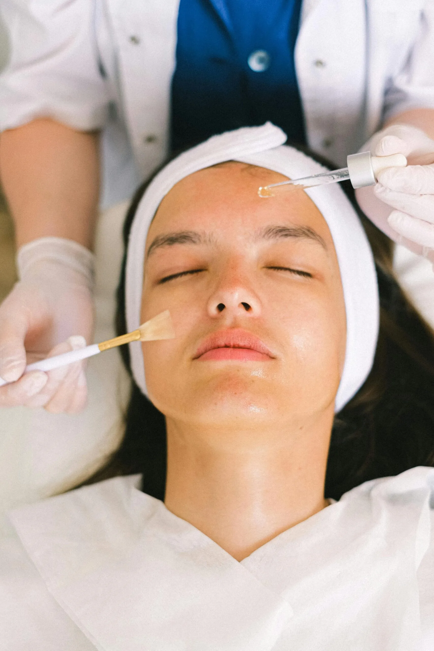 Esthetician applying facial serum during a skin-care treatment