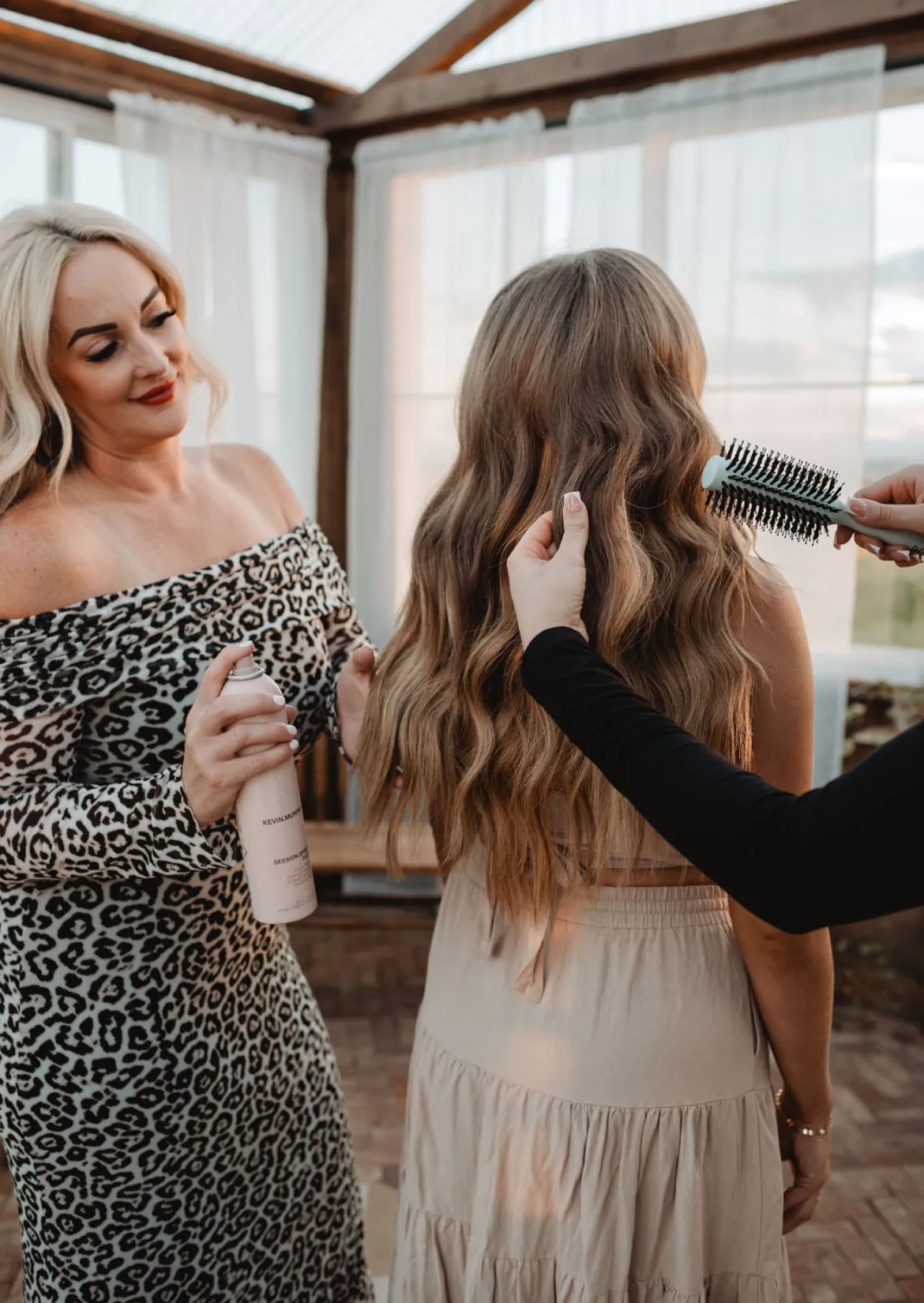 Two Elevate stylists styling a client's hair in the sunlit studio