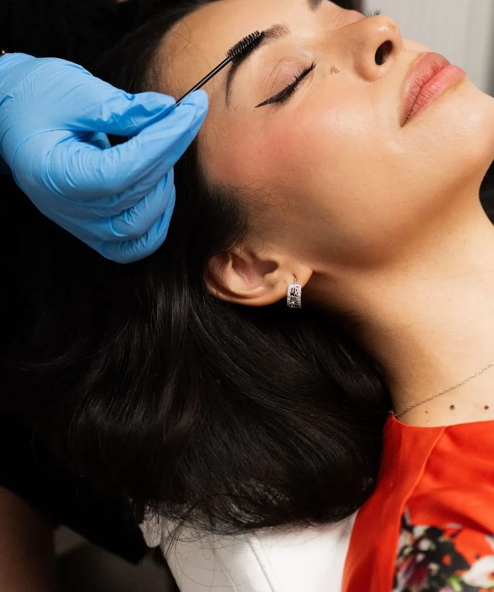 An Elevate student shaping a guest’s brows during a skin-care service